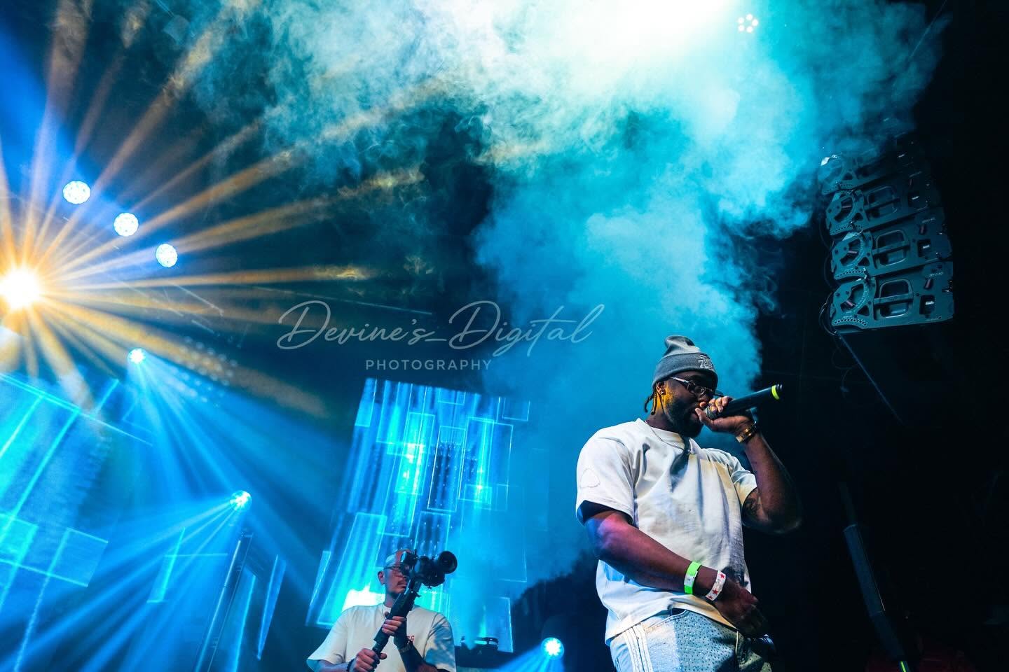 JayDubb Tha Ruler performs beneath blue stage lights and smoke
